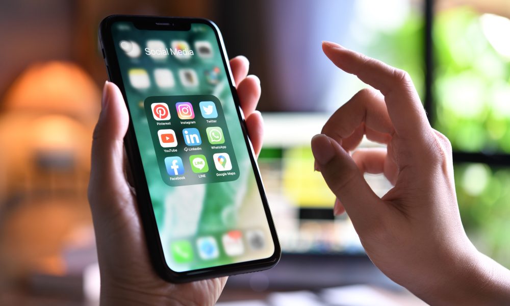 BANGKOK, THAILAND - MARCH 30,2020: Female holding Iphone xr with icons of social media on the screen at home