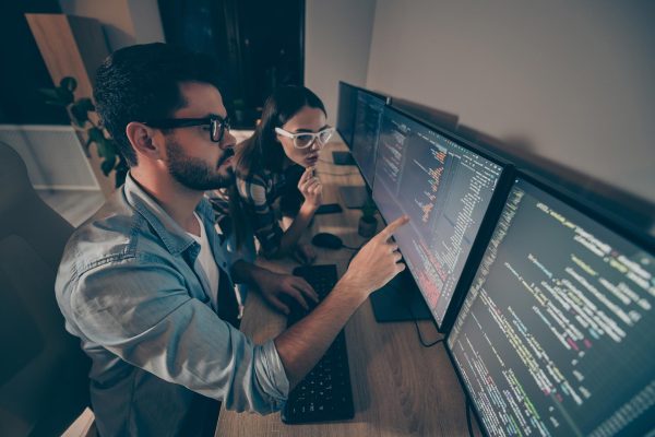 Profile photo of it specialist guy lady two business people late night coworking, watch direct monitor bugs testing java script code geek crazy professionals office indoors