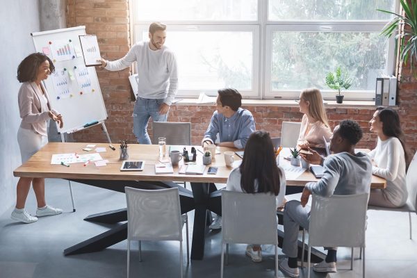 Business partners man and woman making presentation for young creative team in modern office, free space